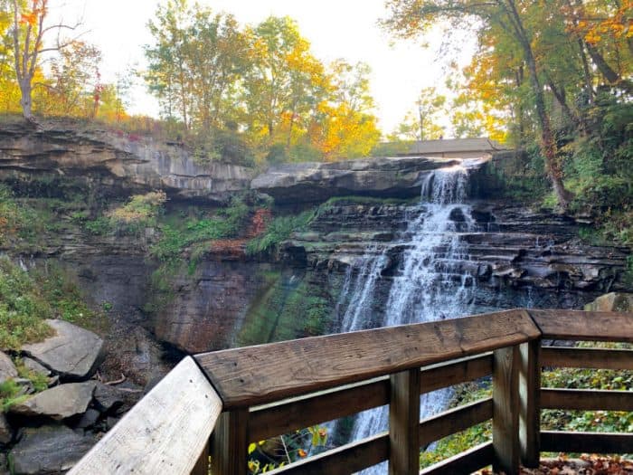 Close up view of a waterfall over a wall of rocks standing from a wooden viewing area