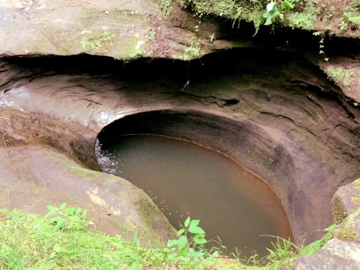 Close up view of a smooth oval hold carved into concrete holding water