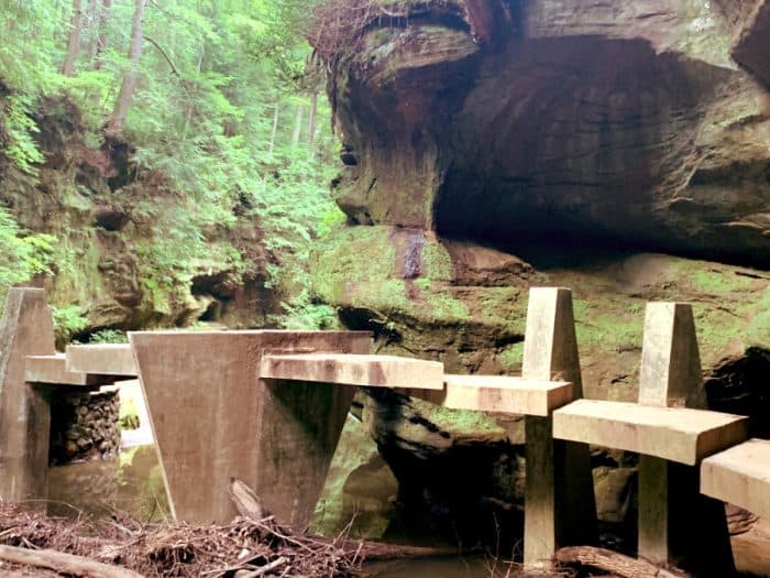 Concrete bridge of individual steps across a shallow pond in a forest