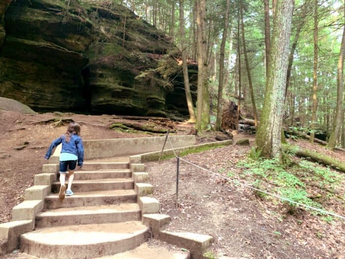 Young girl walking up concrete steps on a path through the forest