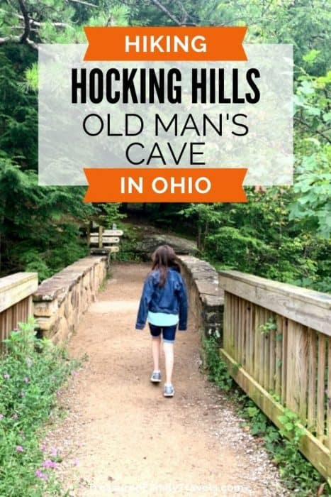Young girl walking across a wooden and stone bridge on a dirt trail in a forest